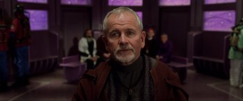 Movie still from “The Fifth Element” (1997), directed by Luc Besson – An older man with a gray beard is looking at the camera; Close Up shot, Low angle