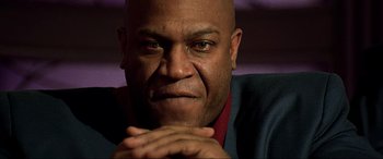 Movie still from “The Fifth Element” (1997), directed by Luc Besson – A bald man with his chin resting on his hands; Close Up shot, Low angle