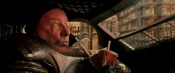 Movie still from “The Fifth Element” (1997), directed by Luc Besson – A man sitting in a car holding a cup of coffee; Close Up shot, Low angle