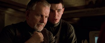 Movie still from “The Fifth Element” (1997), directed by Luc Besson – A man standing next to another man in a room; Close Up shot, Over the shoulder angle