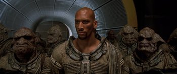 Movie still from “The Fifth Element” (1997), directed by Luc Besson – A man with a bald head and a bunch of other men; Medium shot, High angle