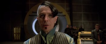 Movie still from “The Fifth Element” (1997), directed by Luc Besson – A man in a striped vest with a white strip on his head; Close Up shot, Over the shoulder angle