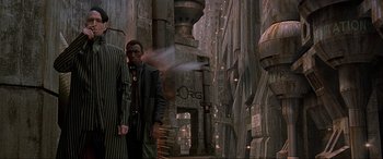 Movie still from “The Fifth Element” (1997), directed by Luc Besson – A man standing next to another man on a city street; Wide shot, Low angle