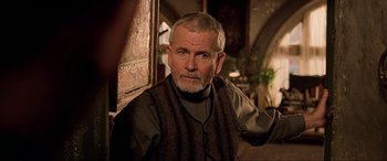 Movie still from “The Fifth Element” (1997), directed by Luc Besson – An older man with a beard and a vest; Close Up shot, Over the shoulder angle