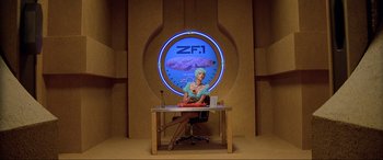 Movie still from “The Fifth Element” (1997), directed by Luc Besson – A woman sitting at a desk in front of a clock; Wide shot, Low angle