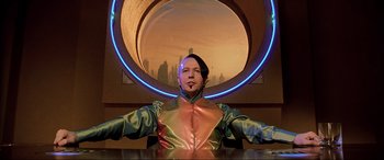Movie still from “The Fifth Element” (1997), directed by Luc Besson – A man in a green and red suit with a blue ring around him; Medium shot, Low angle