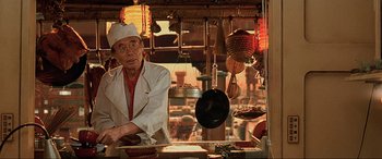 Movie still from “The Fifth Element” (1997), directed by Luc Besson – An old man standing in front of a counter; Medium shot, Low angle