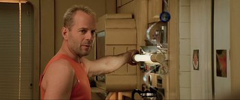 Movie still from “The Fifth Element” (1997), directed by Luc Besson – A man in an orange shirt is putting something in the oven; Close Up shot, Low angle