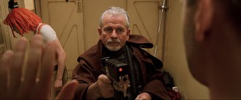 Movie still from “The Fifth Element” (1997), directed by Luc Besson – An older man holding a video camera in a room; Close Up shot, Over the shoulder angle