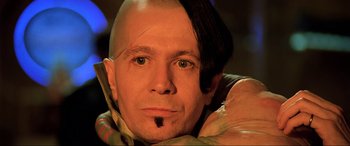 Movie still from “The Fifth Element” (1997), directed by Luc Besson – A man with a shaved head is posing for a picture; Close Up shot, High angle