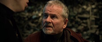 Movie still from “The Fifth Element” (1997), directed by Luc Besson – An older man with a gray beard looking to his left; Close Up shot, Over the shoulder angle