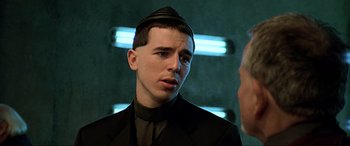 Movie still from “The Fifth Element” (1997), directed by Luc Besson – A man in a black suit and a black hat; Close Up shot, Over the shoulder angle