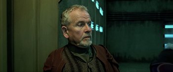 Movie still from “The Fifth Element” (1997), directed by Luc Besson – An older man with grey hair wearing a brown jacket; Close Up shot, Over the shoulder angle