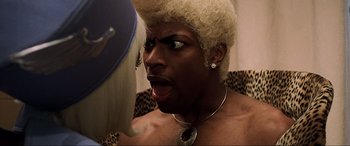 Movie still from “The Fifth Element” (1997), directed by Luc Besson – A man with a blonde wig and a black shirt; Close Up shot, Over the shoulder angle