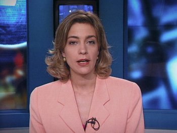 Movie still from “The Figo Affair: The Transfer that Changed Football” (2022), directed by Ben Nicholas – A woman in a pink jacket is in a news studio; Close Up shot, Low angle