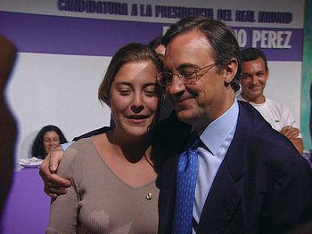 Movie still from “The Figo Affair: The Transfer that Changed Football” (2022), directed by Ben Nicholas – A man and a woman are hugging in front of a group of people; Close Up shot, Low angle