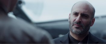 Movie still from “Deadpool” (2016), directed by Tim Miller – A person wearing a suit in a car; Close Up shot, Over the shoulder angle