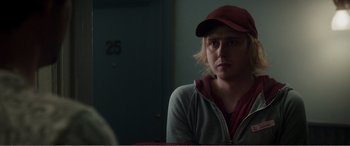 Movie still from “Deadpool” (2016), directed by Tim Miller – A woman wearing a red hat sitting in front of a door; Close Up shot, Over the shoulder angle