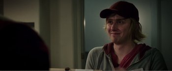 Movie still from “Deadpool” (2016), directed by Tim Miller – A man wearing a hat sitting in front of a table; Close Up shot, Over the shoulder angle