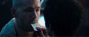 Movie still from “Deadpool” (2016), directed by Tim Miller – A man is holding a piece of paper in his mouth; Extreme Close Up shot, Over the shoulder angle