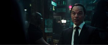 Movie still from “Deadpool” (2016), directed by Tim Miller – A man in a suit and tie in front of a bar; Close Up shot, Over the shoulder angle
