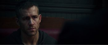 Movie still from “Deadpool” (2016), directed by Tim Miller – A person sitting in a booth; Close Up shot, Over the shoulder angle