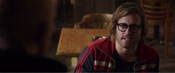 Movie still from “Deadpool” (2016), directed by Tim Miller – A man sitting at a table wearing glasses and a red jacket; Close Up shot, Over the shoulder angle