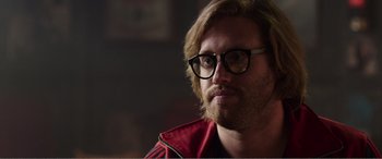 Movie still from “Deadpool” (2016), directed by Tim Miller – A person wearing glasses and a red jacket; Close Up shot, Over the shoulder angle