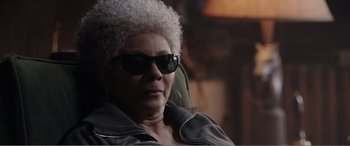 Movie still from “Deadpool” (2016), directed by Tim Miller – An older woman wearing sunglasses sitting in a chair; Close Up shot, Over the shoulder angle
