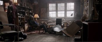 Movie still from “Deadpool” (2016), directed by Tim Miller – A man sitting in a chair in front of a pile of boxes; Wide shot, High angle
