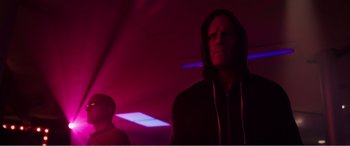 Movie still from “Deadpool” (2016), directed by Tim Miller – A man wearing a hooded sweatshirt standing in front of a light; Medium shot, Low angle