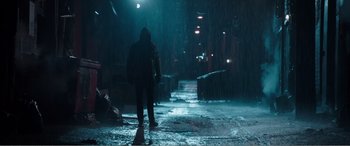 Movie still from “Deadpool” (2016), directed by Tim Miller – A person walking down a street in the rain at night; Wide shot, Low angle