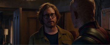 Movie still from “Deadpool” (2016), directed by Tim Miller – A man with a beard wearing glasses and a brown jacket; Close Up shot, Over the shoulder angle