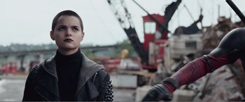 Movie still from “Deadpool” (2016), directed by Tim Miller – A woman in a leather jacket standing in front of a crane; Close Up shot, Over the shoulder angle