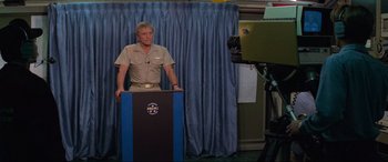 A man standing at a podium in front of a camera