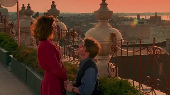 Movie still from “The Firm” (1993), directed by Sydney Pollack – A man kneeling down next to a woman on a balcony; Wide shot, High angle