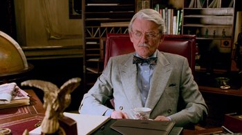 Movie still from “The Firm” (1993), directed by Sydney Pollack – An older man sitting at a desk in a suit and tie; Close Up shot, Low angle