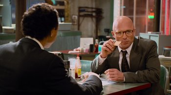 Movie still from “The Firm” (1993), directed by Sydney Pollack – Two people sitting at a table in front of each other eating; Medium shot, Over the shoulder angle