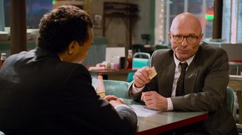 Movie still from “The Firm” (1993), directed by Sydney Pollack – Two people sitting at a table in front of each other at a restaurant; Medium shot, Over the shoulder angle