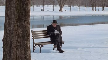 Movie still from “The Firm” (1993), directed by Sydney Pollack – An older man sitting on a bench in the snow; Wide shot, High angle