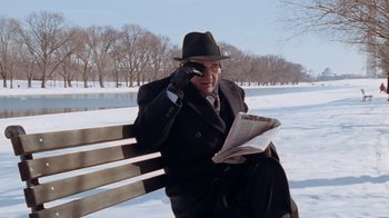 Movie still from “The Firm” (1993), directed by Sydney Pollack – An older man sitting on a park bench talking on a cell phone; Medium shot, Low angle