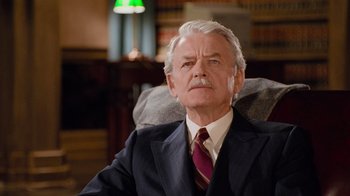 Movie still from “The Firm” (1993), directed by Sydney Pollack – An older man wearing a suit and tie in an office setting; Close Up shot, Low angle