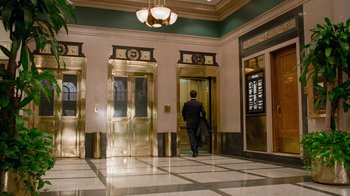 Movie still from “The Firm” (1993), directed by Sydney Pollack – A man in a black suit is in an elevator; Wide shot, Low angle