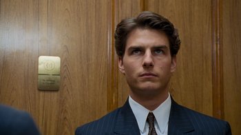 Movie still from “The Firm” (1993), directed by Sydney Pollack – A man wearing a suit and tie standing in front of a door; Close Up shot, Low angle
