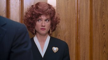 Movie still from “The Firm” (1993), directed by Sydney Pollack – A woman with red curly hair and a heart shaped pin; Close Up shot, Over the shoulder angle