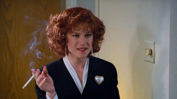 Movie still from “The Firm” (1993), directed by Sydney Pollack – A woman with red curly hair wearing a black suit; Close Up shot, Over the shoulder angle