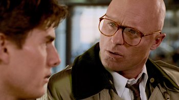 Movie still from “The Firm” (1993), directed by Sydney Pollack – A man with glasses is talking to another man; Close Up shot, Over the shoulder angle