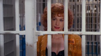 Movie still from “The Firm” (1993), directed by Sydney Pollack – A woman with red curly hair standing behind bars; Medium shot, Over the shoulder angle