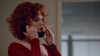 Movie still from “The Firm” (1993), directed by Sydney Pollack – A woman with red hair is talking on a phone and smoking a cigarette; Close Up shot, Low angle