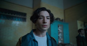 Movie still from “The Flash” (2023), directed by Andy Muschietti – A man with long black hair is standing in a room; Close Up shot, High angle